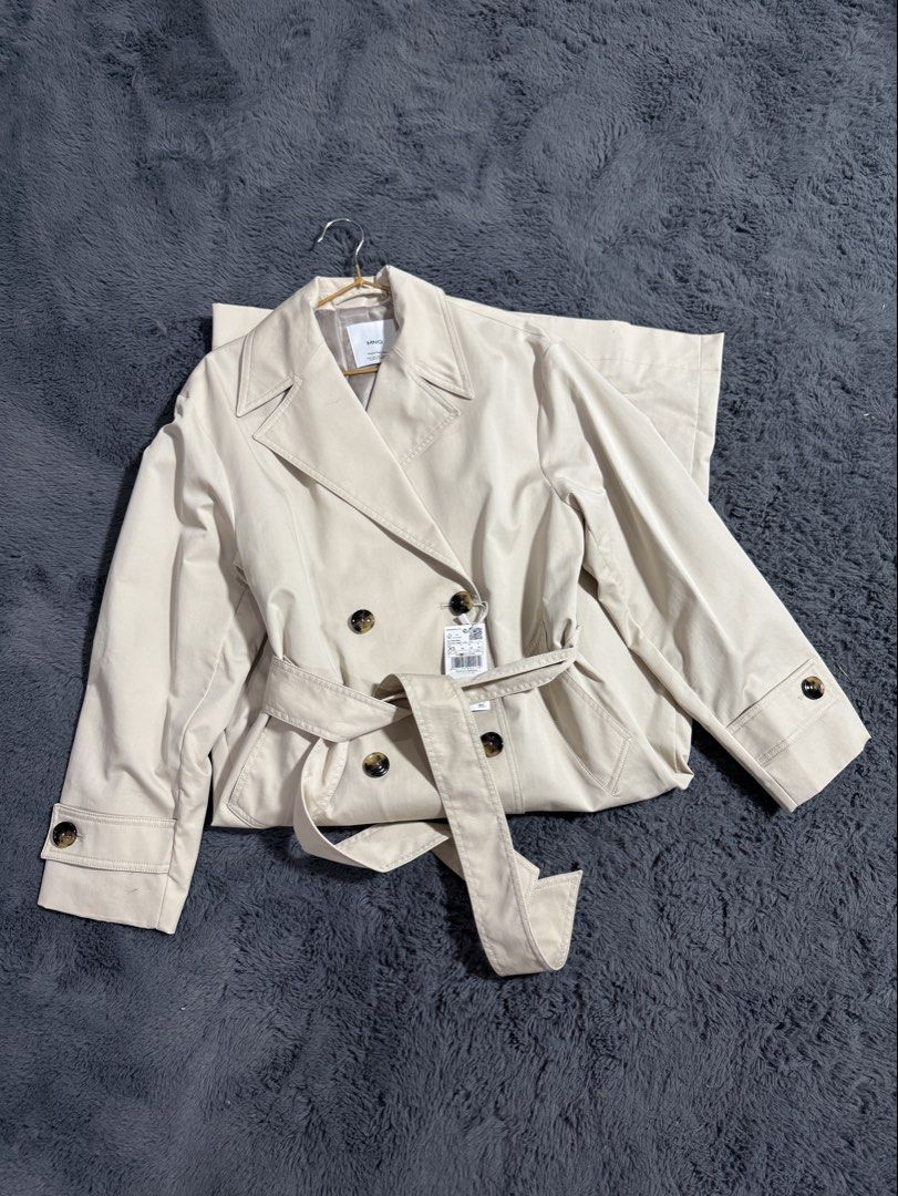Mango Trench Coat Angela Beige (Category: Coats, Jackets and Outerwear) located in Las Pinas. Submitted by juls_mp (Listing ID 1468428699, Image 1). Description: - Brand: Mango (Angela model) - Color: Classic beige - Condition: Brand new with original store tags - Original Retail Price: ₱6,595 - Features: Double-breasted front, tortoise shell buttons, matching tie belt - Details: Structured collar, button tabs on cuffs - Fit/Material: Lightweight