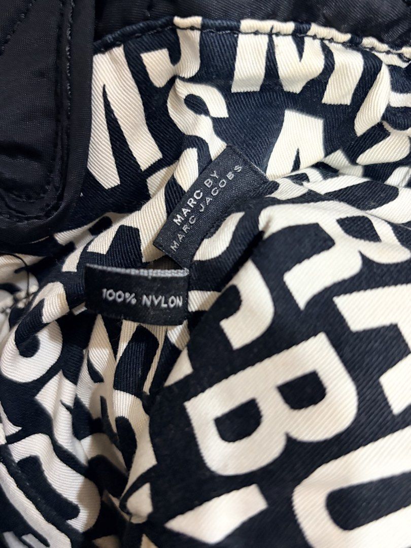 Marc by Marc Jacobs Quilted Nylon Tote Bag (Category: Tote Bags) located in Quezon City. Submitted by pattycloset08 (Listing ID 1468425884, Image 3). Description: - Brand: Marc by Marc Jacobs - Style: Quilted nylon tote bag with iconic standard supply metal patch - Material: 100% durable black nylon - Straps: Dual handle straps with stylish knotted accents - Interior: Signature black and white monogram fabric lining with a secure zippered pocket 