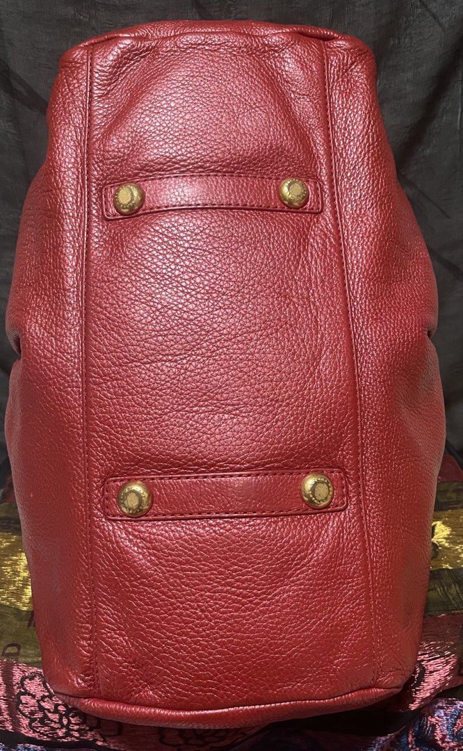 Marc by Marc Jacobs Red Leather Handbag (Category: Luxury Bags & Wallets) located in Manila. Submitted by ermenchita71969 (Listing ID 1468452551, Image 3). Description: - Brand: Marc by Marc Jacobs - Material: Premium red pebbled leather with gold-tone hardware - Design: Front strap with metallic logo plaque and structured rectangular base - Closure & Handles: Zippered top closure with comfortable rolled top handles - Interior: Signature monogram