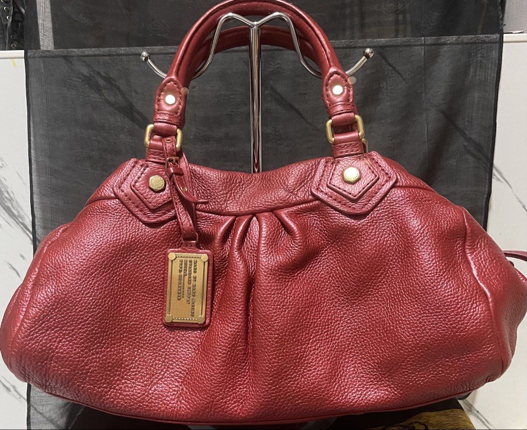 Marc by Marc Jacobs Red Leather Handbag (Category: Luxury Bags & Wallets) located in Manila. Submitted by ermenchita71969 (Listing ID 1468452551, Image 1). Description: - Brand: Marc by Marc Jacobs - Material: Premium red pebbled leather with gold-tone hardware - Design: Front strap with metallic logo plaque and structured rectangular base - Closure & Handles: Zippered top closure with comfortable rolled top handles - Interior: Signature monogram