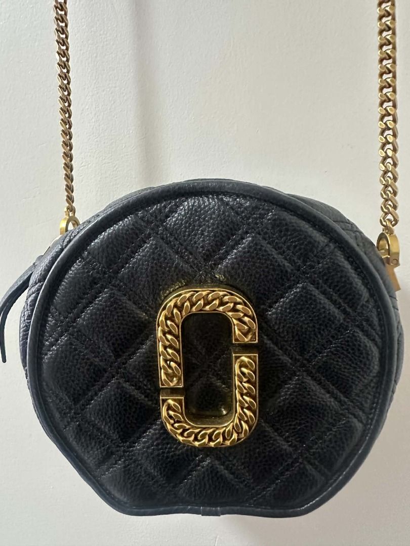 Marc Jacobs Black Quilted Round Crossbody Bag (Category: Cross-body Bags) located in Angeles City. Submitted by mycloset525clotheshoppe (Listing ID 1468290526, Image 1). Description: - Brand: Marc Jacobs - Style: Round crossbody bag - Material: Black quilted leather - Hardware: Chunky gold chain monogram logo and matching chain strap - Closure: Side zip closure - Condition: Minor wear on the metal logo, perfect size for daily essentials.
