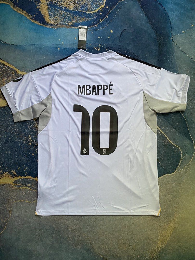Mbappé Jersey (Category: Activewear) located in Abucay. Submitted by lili_pretty (Listing ID 1468420899, Image 1). Description: - Brand: Adidas - Player/Team: Mbappé (Real Madrid home jersey style) - Size: 2XL (Slim Fit) - Color: White with black accents - Condition: Brand new with tags - Features: Embroidered logo, high-quality fabric .