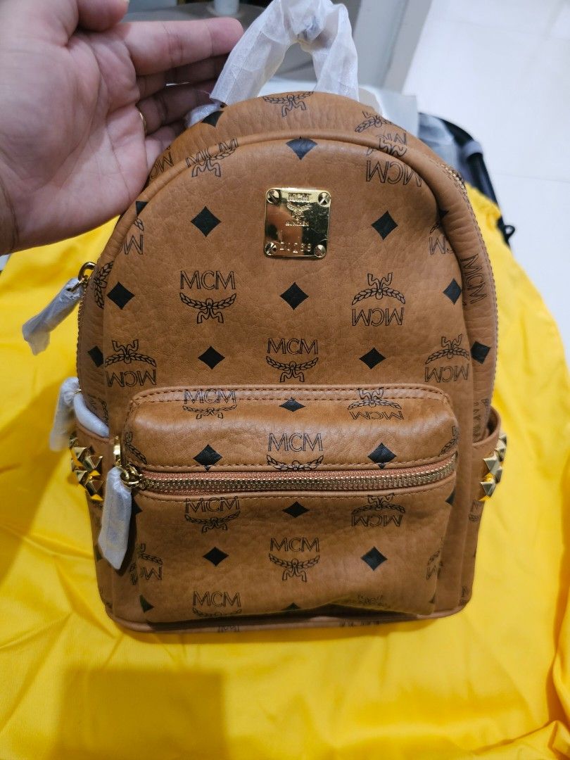 MCM Stark Visetos Studded Backpack (Category: Backpacks) located in Manila. Submitted by carmi2409 (Listing ID 1468333813, Image 1). Description: - Brand: MCM (Cognac Visetos Monogram Coated Canvas) - Condition: Brand new, unused, with original store tags attached - Hardware: Gold-tone with edgy pyramid studs along the sides and top - Compartments: Front zip pocket and secure two-way top zip closure - Straps: Adjustable webbed straps, still wrapp