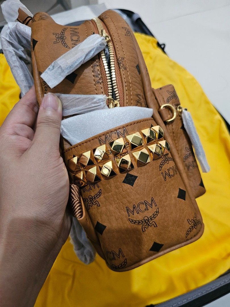 MCM Stark Visetos Studded Backpack (Category: Backpacks) located in Manila. Submitted by carmi2409 (Listing ID 1468333813, Image 3). Description: - Brand: MCM (Cognac Visetos Monogram Coated Canvas) - Condition: Brand new, unused, with original store tags attached - Hardware: Gold-tone with edgy pyramid studs along the sides and top - Compartments: Front zip pocket and secure two-way top zip closure - Straps: Adjustable webbed straps, still wrapp