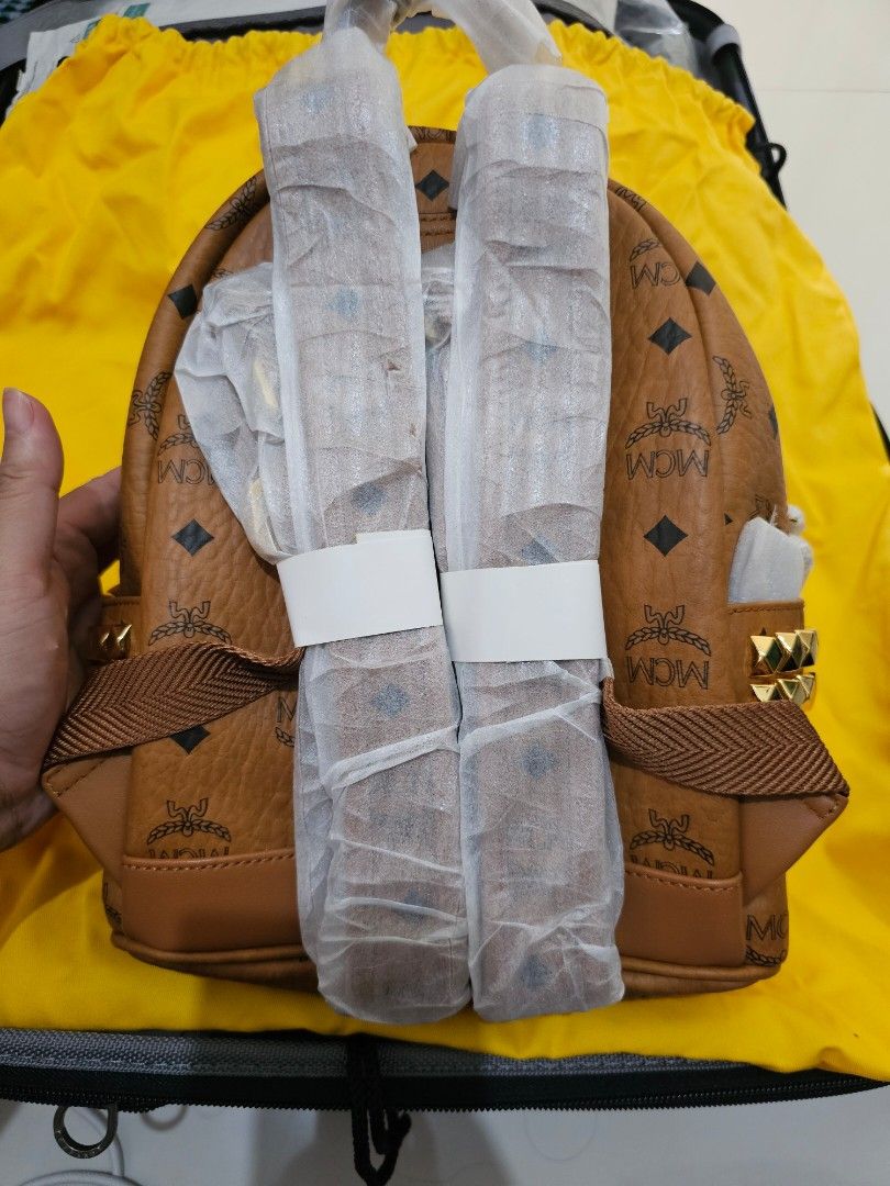 MCM Stark Visetos Studded Backpack (Category: Backpacks) located in Manila. Submitted by carmi2409 (Listing ID 1468333813, Image 2). Description: - Brand: MCM (Cognac Visetos Monogram Coated Canvas) - Condition: Brand new, unused, with original store tags attached - Hardware: Gold-tone with edgy pyramid studs along the sides and top - Compartments: Front zip pocket and secure two-way top zip closure - Straps: Adjustable webbed straps, still wrapp