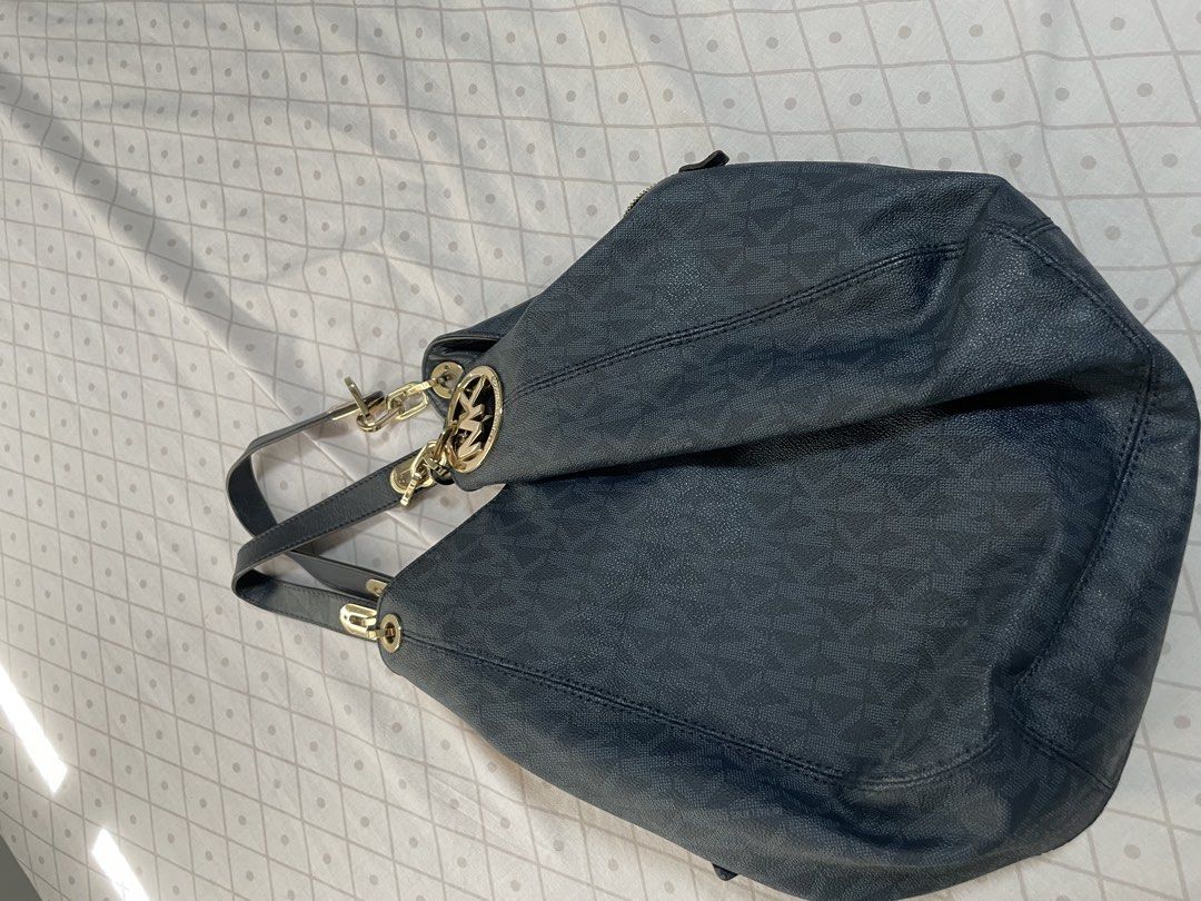 Michael Kors Black Monogram Hobo Shoulder Bag (Category: Luxury Bags & Wallets) located in Quezon City. Submitted by tor_ash (Listing ID 1468322405, Image 3). Description: Michael Kors hobo bag in dark monogram print. Textured finish, gold hardware, and metal MK circle logo rings on the straps. Interior lined in light fabric with a zip pocket and slip pockets. Zip closure across the top. Spacious slouchy shape, comfortable to carry on the shoulde