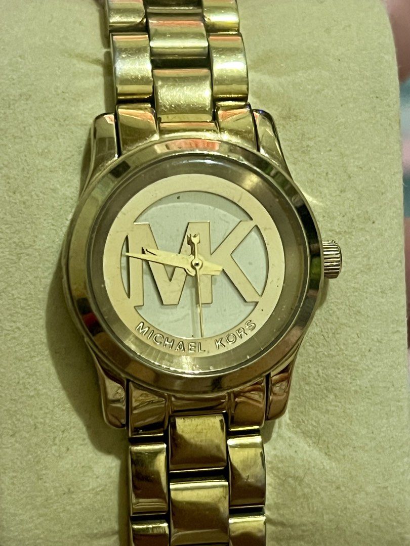 Michael Kors Gold Watch with MK Logo Dial (Category: Women's Watches) located in Dagupan City. Submitted by casadebayongph (Listing ID 1468327367, Image 2). Description: - Brand: Michael Kors - Color: Polished gold-tone finish - Design: Statement watch with large MK logo on the face - Closure: Link bracelet with branded deployment clasp - Condition: Good pre-loved condition with minor hairline scratches on links from normal wear - Style: Elegant,