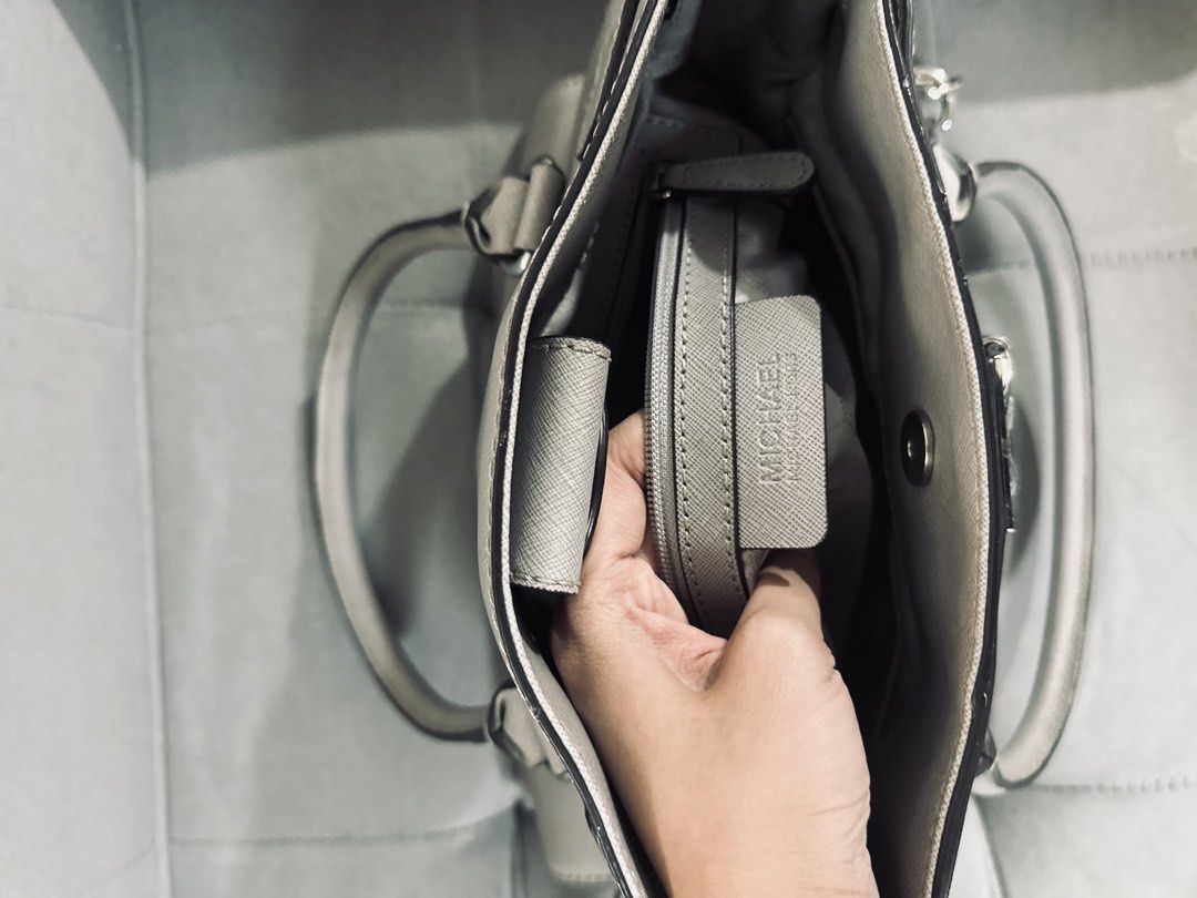 Michael Kors Gray Studded Satchel Handbag (Category: Luxury Bags & Wallets) located in Tarlac. Submitted by via_banana (Listing ID 1468352049, Image 3). Description: - Brand: Michael Kors - Material: Durable gray Saffiano leather - Hardware: Silver-tone with chic padlock accent and side chain links - Compartments: Center zip divider with multiple interior slip and zip pockets - Straps: Double top handles and an adjustable/removable shoulder strap
