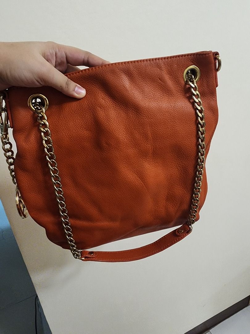 Michael Kors Orange Leather Shoulder Bag with Chain Strap (Category: Luxury Bags & Wallets) located in Caloocan City. Submitted by keenmoon.752ef0 (Listing ID 1466938475, Image 3). Description: - Brand/Model: Authentic Michael Kors leather handbag - Color: Bright orange with shiny gold-tone hardware - Material: Soft and durable pebble leather - Features: Signature MK logo charm and chain straps - Strap: Extra long strap rolled up and attached in 