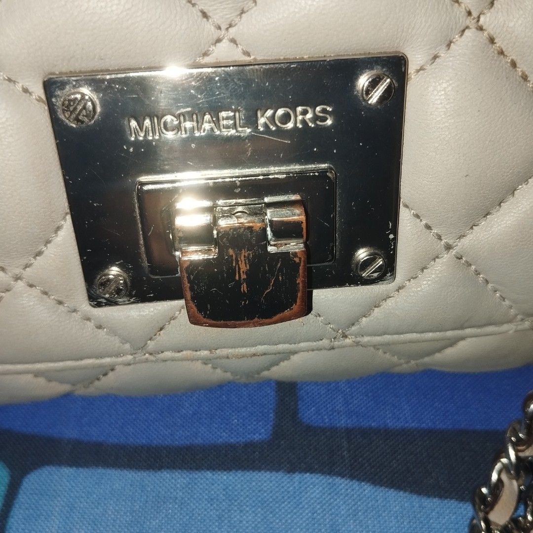 Michael Kors Quilted Shoulder Bag with Chain Strap (Category: Cross-body Bags) located in Manila. Submitted by lene48 (Listing ID 1468388760, Image 2). Description: - Brand: Michael Kors - Style: Quilted leather shoulder bag - Color: Soft greyish-beige - Hardware: Silver-tone chain strap interwoven with leather and engraved turn-lock closure - Condition: Pre-loved with visible wear and scuffing on the metallic turn-lock and edges, chain still pol