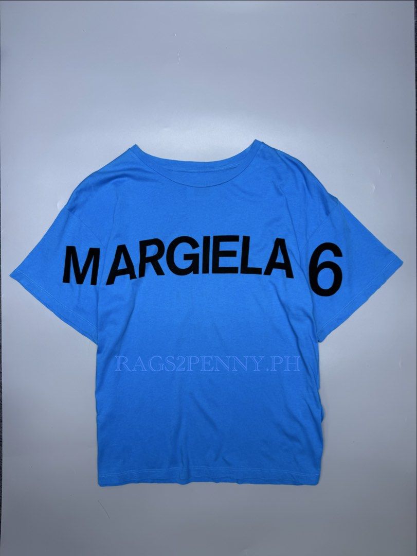 MM6 Maison Margiela (Category: Luxury Apparel) located in Kabacan. Submitted by rags2penny.phl (Listing ID 1468337182, Image 1). Description: - Brand: MM6 Maison Margiela - Color: Bright blue with large black graphic print and branding - Material: 100% premium cotton, made in Romania - Size: 12 (Tag on collar) - Design: Short sleeves, classic crew neck - Condition: Clean overall Measurements : 21.5 x 25.