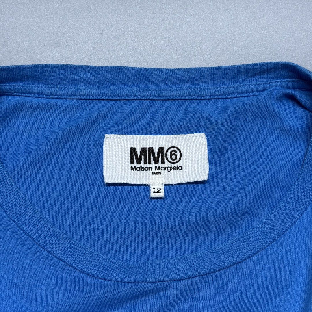 MM6 Maison Margiela (Category: Luxury Apparel) located in Kabacan. Submitted by rags2penny.phl (Listing ID 1468337182, Image 3). Description: - Brand: MM6 Maison Margiela - Color: Bright blue with large black graphic print and branding - Material: 100% premium cotton, made in Romania - Size: 12 (Tag on collar) - Design: Short sleeves, classic crew neck - Condition: Clean overall Measurements : 21.5 x 25.
