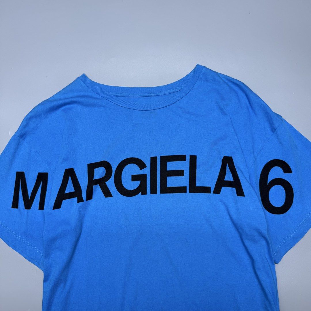MM6 Maison Margiela (Category: Luxury Apparel) located in Kabacan. Submitted by rags2penny.phl (Listing ID 1468337182, Image 2). Description: - Brand: MM6 Maison Margiela - Color: Bright blue with large black graphic print and branding - Material: 100% premium cotton, made in Romania - Size: 12 (Tag on collar) - Design: Short sleeves, classic crew neck - Condition: Clean overall Measurements : 21.5 x 25.