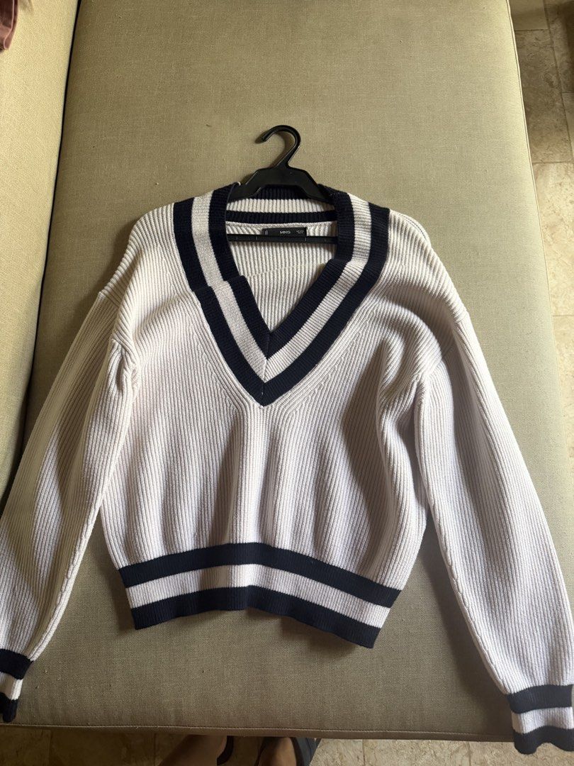MNG White V-Neck Cricket Sweater (Category: Longsleeves) located in Angeles City. Submitted by reginageorge22 (Listing ID 1468329506, Image 3). Description: - Style: Classic preppy look with white knit and navy blue stripes - Details: V-neck, cuffs, and hem accents with ribbed texture - Fit: Relaxed fit, Tag size L - Perfect for: Cooler weather staple piece See photos re minor flaws I'm usually a size small kaso I like this sweater a lot pero lag
