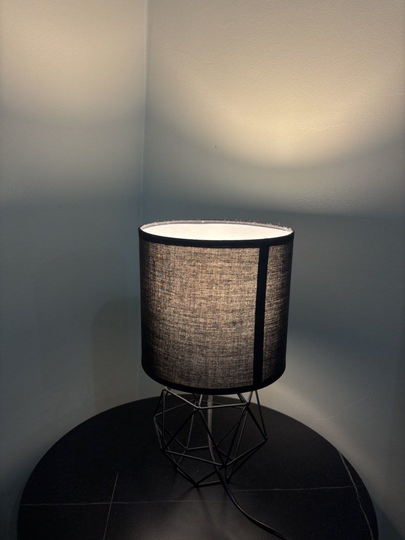 Modern Black Geometric Wire Table Lamp with Fabric Shade (Category: Lighting) located in Cavite. Submitted by xxjxt (Listing ID 1468407744, Image 3). Description: - Stylish black cylindrical fabric shade with open geometric wire base - Emits a warm and cozy glow, perfect for relaxing - Convenient inline toggle switch on the cord - Versatile design great for bedside tables, desks, or living room side tables - Bulb already included for your conveni