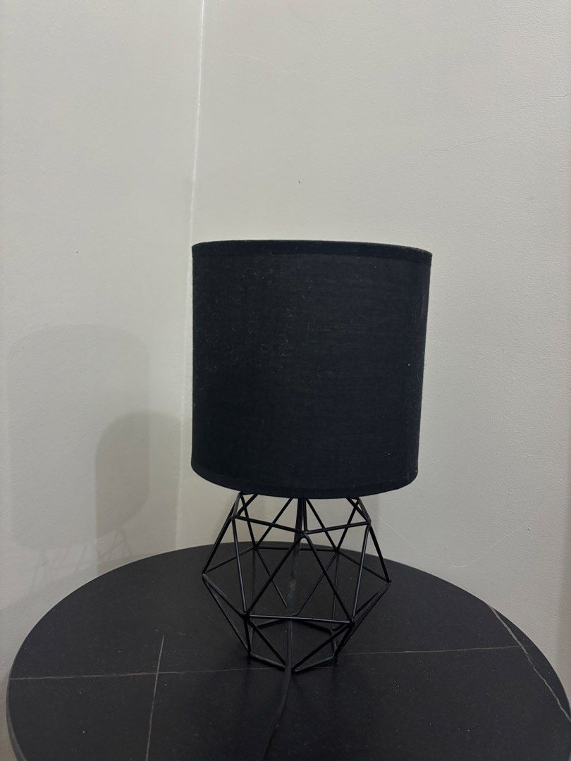 Modern Black Geometric Wire Table Lamp with Fabric Shade (Category: Lighting) located in Cavite. Submitted by xxjxt (Listing ID 1468407744, Image 1). Description: - Stylish black cylindrical fabric shade with open geometric wire base - Emits a warm and cozy glow, perfect for relaxing - Convenient inline toggle switch on the cord - Versatile design great for bedside tables, desks, or living room side tables - Bulb already included for your conveni