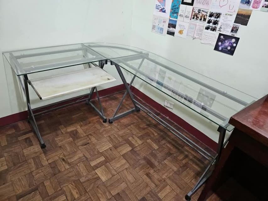 Modern L-Shaped Glass Corner Computer Desk with Keyboard Tray (Category: Tables & Sets) located in Pasig City. Submitted by rnr2026 (Listing ID 1468306380, Image 1). Description: - Clear glass top corner desk with a sleek silver metal frame - Features a convenient pull-out sliding keyboard tray on the left section - Sturdy X-frame support legs for maximum stability - Generous workspace ideal for multiple monitors and accessories - Space-saving de