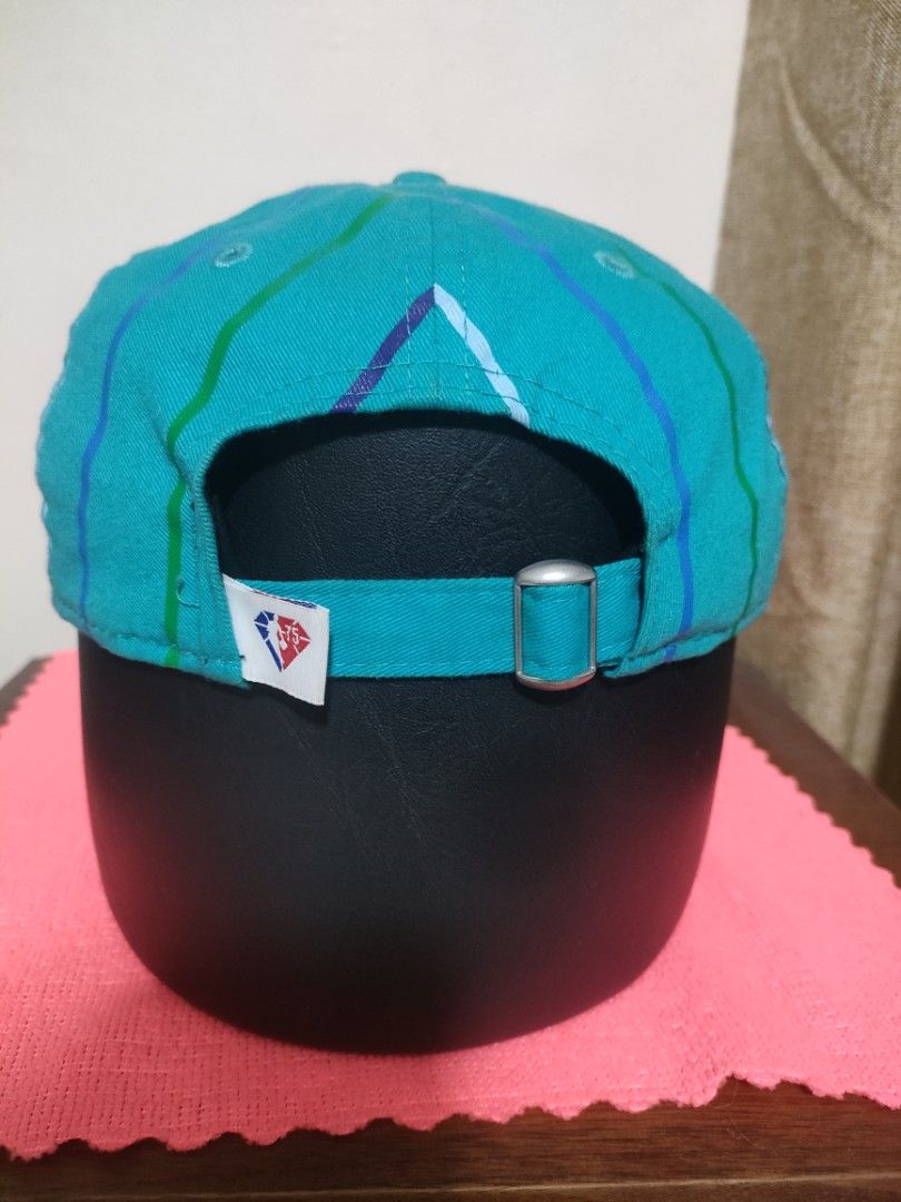 New Era Charlotte Hornets 9TWENTY Adjustable Cap (Category: Caps & Hats) located in Santa Rosa. Submitted by abj_104 (Listing ID 1468304860, Image 2). Description: - Authentic New Era 9TWENTY Cap in Teal - Features embroidered Charlotte script on the front - Unique striped vertical pattern on the crown - Rare NBA 75th anniversary tag on the side - Adjustable strapback closure with a silver metal buckle - with original visor sticker still attached