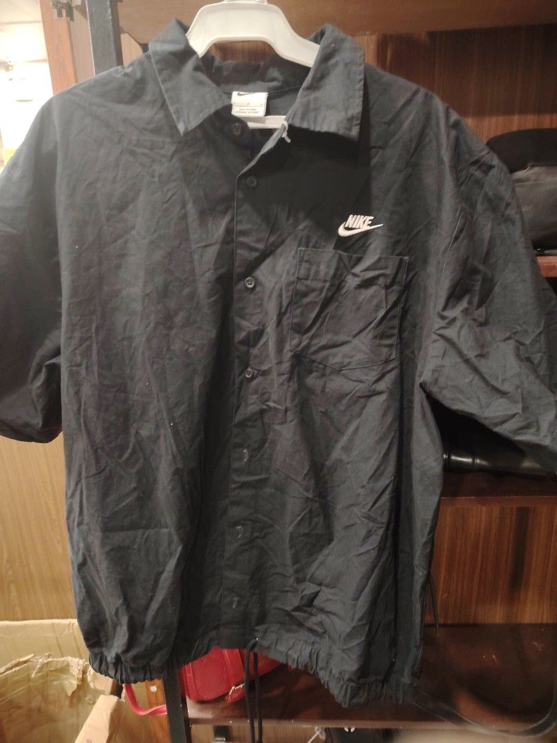 Nike Black Button-Up Shirt with Chest Pocket Size L (Category: Tshirts & Polo Shirts ) located in Calapan. Submitted by thriftopia_12 (Listing ID 1468416607, Image 1). Description: - Brand: Nike - Color: Black - Size: Large - Style: Short-sleeve button-up shirt with classic collar - Details: Single chest pocket with white embroidered Nike logo, front button closure - Hem: Adjustable drawstring hem for a custom fit - Origin: Made in China.