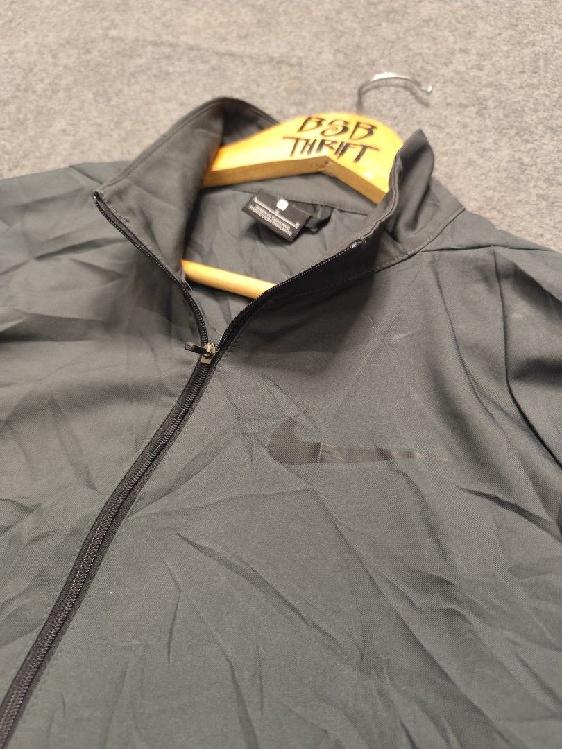 Nike Dri-FIT Grey Zip-Up Windbreaker Jacket (Category: Coats, Jackets and Outerwear) located in Cordova. Submitted by bsb.streetluxvintage.clothing (Listing ID 1468423919, Image 2). Description: - Brand/Model: Nike Dri-FIT zip-up jacket - Color: Dark grey with a subtle black Nike swoosh logo - Size: Large - Material/Design: Lightweight athletic track jacket with a breathable mesh interior lining - Features: Full front zipper closure with a high c