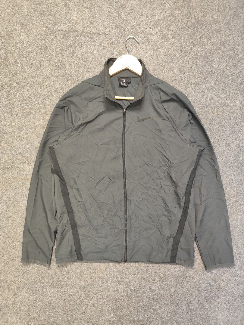 Nike Dri-FIT Grey Zip-Up Windbreaker Jacket (Category: Coats, Jackets and Outerwear) located in Cordova. Submitted by bsb.streetluxvintage.clothing (Listing ID 1468423919, Image 1). Description: - Brand/Model: Nike Dri-FIT zip-up jacket - Color: Dark grey with a subtle black Nike swoosh logo - Size: Large - Material/Design: Lightweight athletic track jacket with a breathable mesh interior lining - Features: Full front zipper closure with a high c