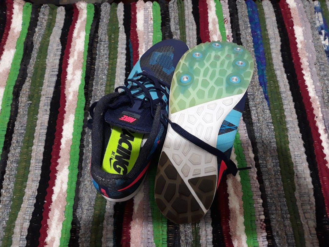 Nike Rival XC Racing Spikes Blue Pink (Category: Sneakers) located in Bulacan. Submitted by beautifulaseverswan (Listing ID 1468291829, Image 2). Description: - Brand: Nike - Model: Rival XC Track & Cross-Country Spikes - Colorway: Blue and black patterned upper with bright pink swoosh - Details: Neon green insoles with printed 'RACING' text, blue laces - Soles: Spike plate with metal pins attached, waffle traction pattern on the heel.