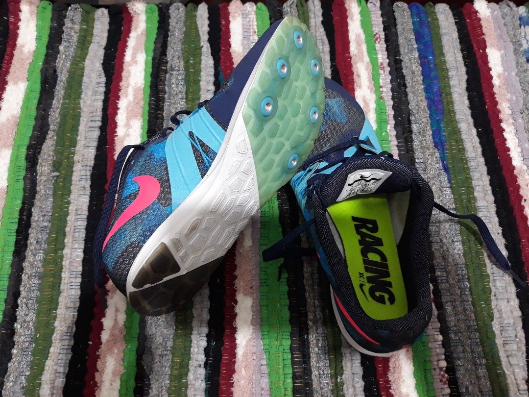 Nike Rival XC Racing Spikes Blue Pink (Category: Sneakers) located in Bulacan. Submitted by beautifulaseverswan (Listing ID 1468291829, Image 1). Description: - Brand: Nike - Model: Rival XC Track & Cross-Country Spikes - Colorway: Blue and black patterned upper with bright pink swoosh - Details: Neon green insoles with printed 'RACING' text, blue laces - Soles: Spike plate with metal pins attached, waffle traction pattern on the heel.