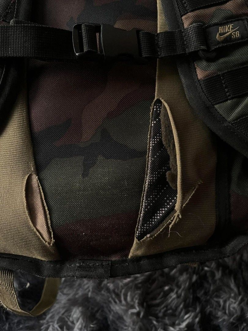 Nike SB Camo Backpack (Category: Backpacks) located in Manila. Submitted by thrift_ni_pambiii (Listing ID 1468344467, Image 2). Description: - Brand: Nike SB - Pattern: Camo with olive green interior lining - Features: Multiple secure zip compartments, heavy-duty front straps, and a front chest buckle strap - Condition: Noticeable tears and fabric damage near the lower back panel area - Best for: Skateboarding, daily commutes, or casual use.