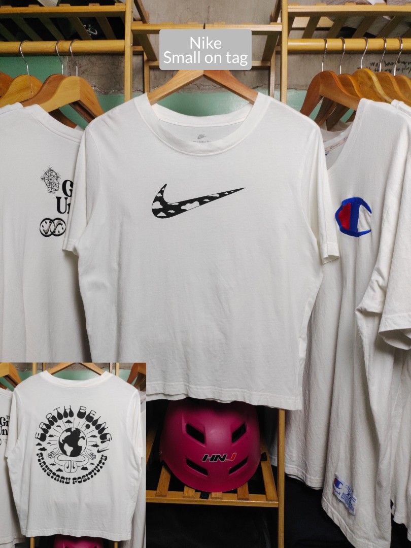 Nike White Graphic (Category: Shirts) located in Tayabas. Submitted by lorrena (Listing ID 1468436321, Image 1). Description: - Brand: Nike - Style: Graphic tee with cow print swoosh and back print - Size: Small - Design Details: Front cow print logo, back 'Earth Being Planetary Positivity' circular graphic, classic crew neck, short sleeves - Condition: Clean and in good shape.
