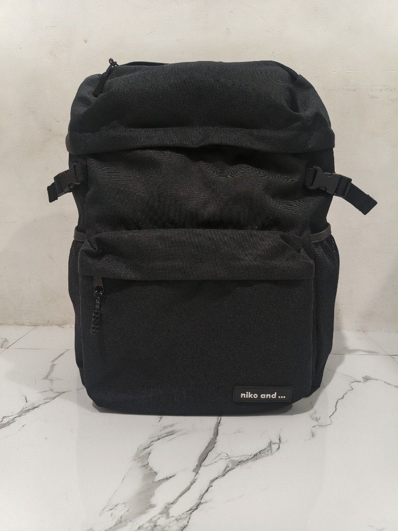 niko and... black canvas backpack (Category: Backpacks) located in Manila. Submitted by obedmagall74424 (Listing ID 1468401069, Image 1). Description: - Brand: niko and... - Color: Classic black - Material: Durable canvas with clean interior lining - Closure: Roll-top style with side buckle compression straps - Pockets: Multiple exterior zip pockets, mesh side pockets, internal zipper compartment, and open slip pockets - Comfort: Padded mesh shou
