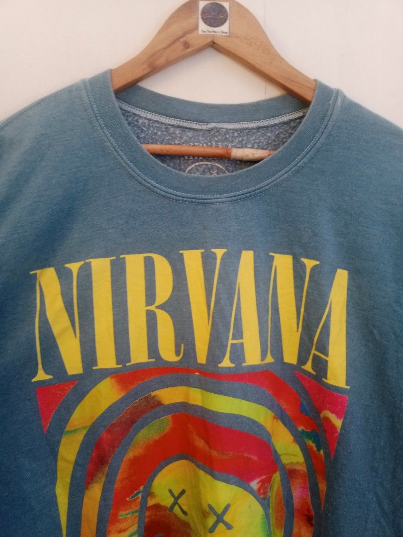 Nirvana Tie Dye Smiley Face Crewneck Sweatshirt Blue (Category: Coats, Jackets and Outerwear) located in Santa Rosa. Submitted by thethriftersshop (Listing ID 1468291156, Image 3). Description: - Color/Wash: Faded blue with vibrant multicolored tie-dye - Design: Iconic Nirvana band logo on front, colorful smiley graphic on chest, and stacked yellow smileys down the left sleeve - Material: 50% cotton, 50% polyester (Made in Honduras) - Measurement