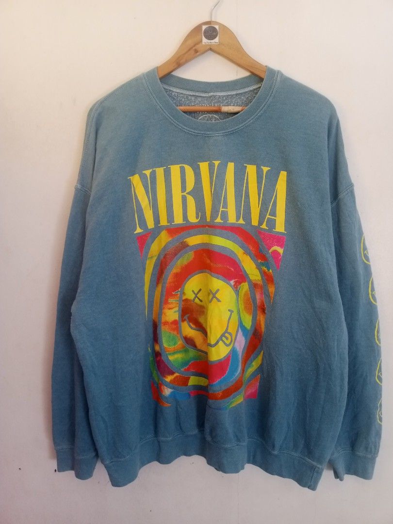 Nirvana Tie Dye Smiley Face Crewneck Sweatshirt Blue (Category: Coats, Jackets and Outerwear) located in Santa Rosa. Submitted by thethriftersshop (Listing ID 1468291156, Image 1). Description: - Color/Wash: Faded blue with vibrant multicolored tie-dye - Design: Iconic Nirvana band logo on front, colorful smiley graphic on chest, and stacked yellow smileys down the left sleeve - Material: 50% cotton, 50% polyester (Made in Honduras) - Measurement