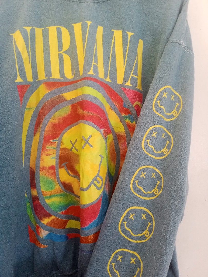 Nirvana Tie Dye Smiley Face Crewneck Sweatshirt Blue (Category: Coats, Jackets and Outerwear) located in Santa Rosa. Submitted by thethriftersshop (Listing ID 1468291156, Image 2). Description: - Color/Wash: Faded blue with vibrant multicolored tie-dye - Design: Iconic Nirvana band logo on front, colorful smiley graphic on chest, and stacked yellow smileys down the left sleeve - Material: 50% cotton, 50% polyester (Made in Honduras) - Measurement