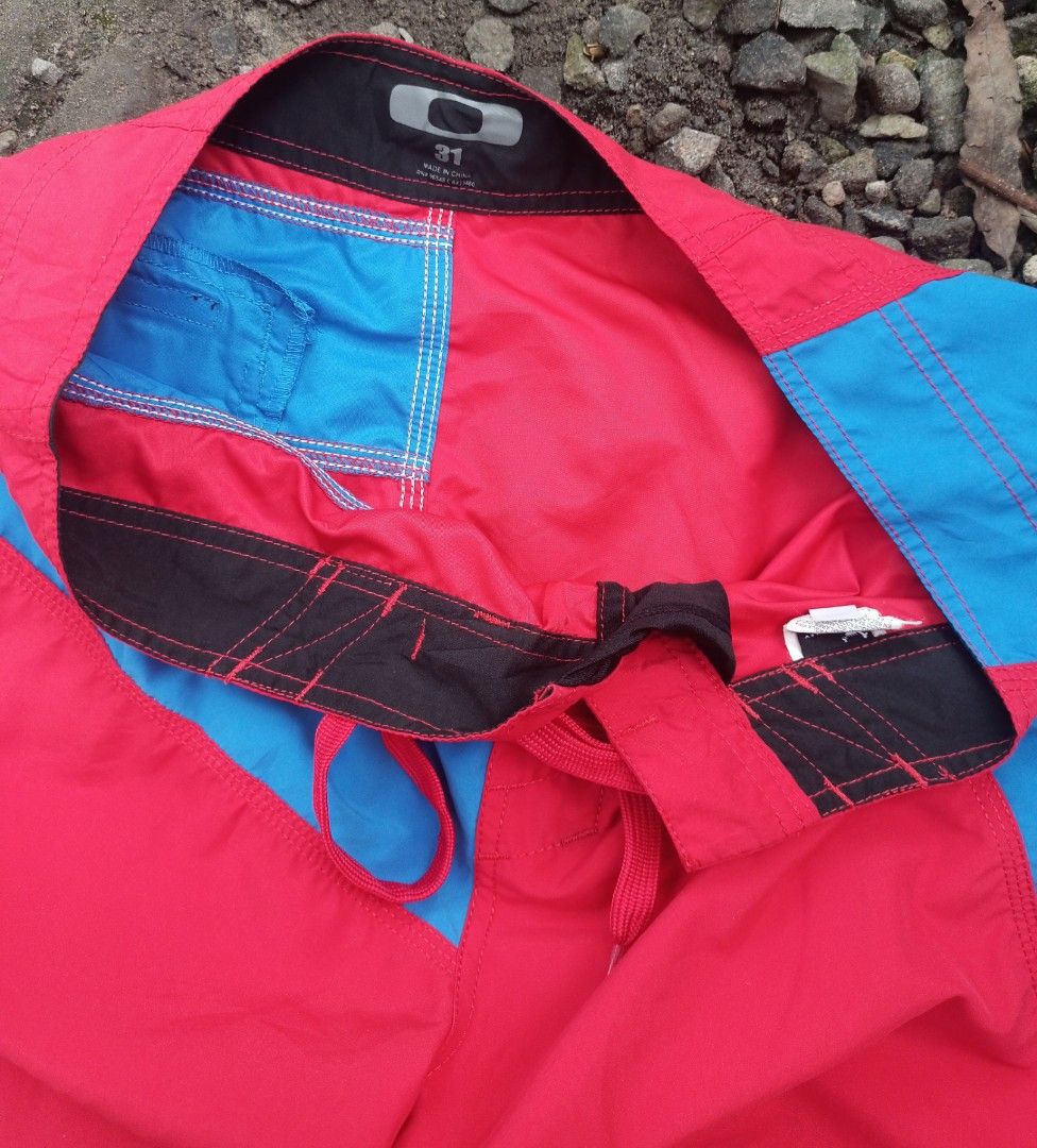 Oakley Board Shorts Red Blue Size 31 (Category: Swim Trunks & Board Shorts) located in Manila. Submitted by vastdolphin.8d68cc (Listing ID 1468325101, Image 2). Description: - Brand: Oakley - Style: Board shorts in a red and blue colourway - Size: 31 waist - Closure: Front drawstring - Pockets: Back pocket with zipper and loop detail - Design: Contrast side panels, subtle hem logo, and back waistband brand patch - Ideal for: Swimming, surfing, an