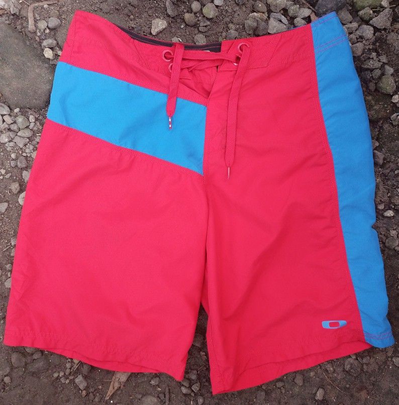 Oakley Board Shorts Red Blue Size 31 (Category: Swim Trunks & Board Shorts) located in Manila. Submitted by vastdolphin.8d68cc (Listing ID 1468325101, Image 3). Description: - Brand: Oakley - Style: Board shorts in a red and blue colourway - Size: 31 waist - Closure: Front drawstring - Pockets: Back pocket with zipper and loop detail - Design: Contrast side panels, subtle hem logo, and back waistband brand patch - Ideal for: Swimming, surfing, an
