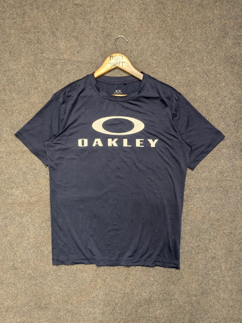 Oakley Performance Fit T-Shirt (Category: Activewear) located in Cordova. Submitted by bsb.streetluxvintage.clothing (Listing ID 1468425204, Image 1). Description: - Brand: Oakley - Color: Navy Blue - Design: Large white Oakley Ellipse logo on chest - Fit/Style: Performance fit - Material: 88% Polyester, 12% Elastane - Size: US/EU Small (JPN Medium) - Condition/Care: Made in China, machine washable.