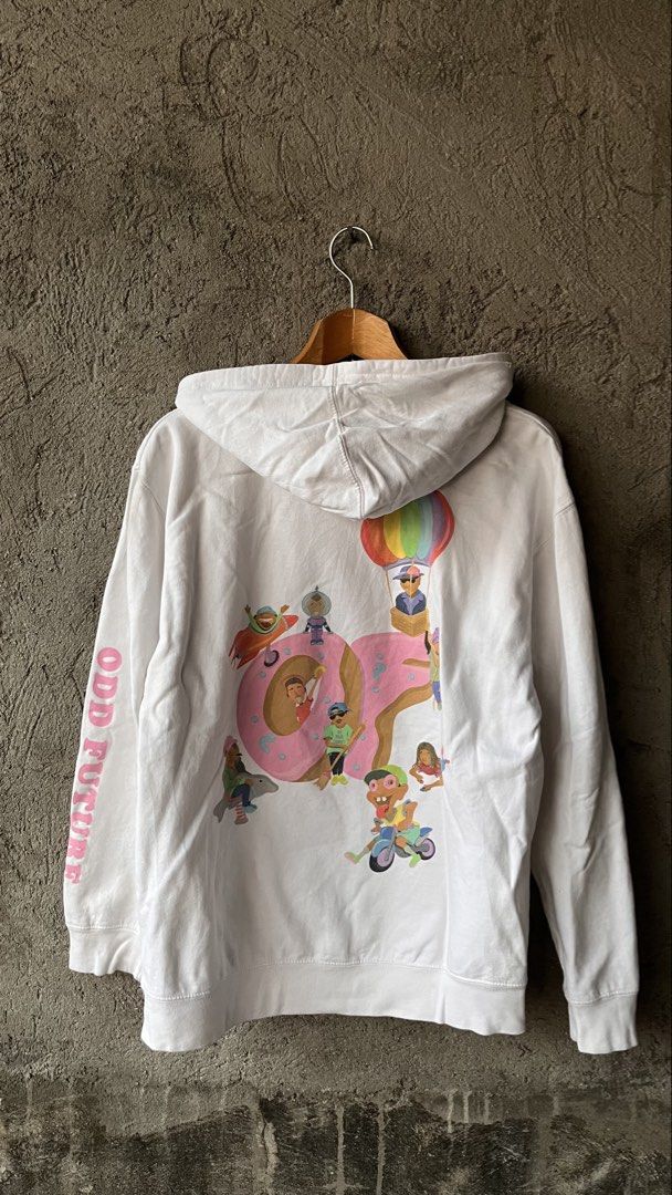 Odd Future Donut White Hoodie Size M (Category: Hoodies) located in Cabuyao City. Submitted by bulandos (Listing ID 1468379631, Image 2). Description: White Odd Future hoodie with the pink donut logo on the chest. Large graphic print on the back featuring cartoon characters around the donut, plus 'Odd Future' text down the left sleeve. Kangaroo pocket in front, drawstring hood. Size medium tag printed inside the collar. 80% cotton, 20% polyester 