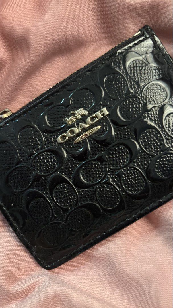 Original Coach Coin purse (Category: Wallets & Card holders) located in Manila. Submitted by coolflower-e6627b (Listing ID 1468339510, Image 2). Description: - Brand: Coach - Material: Black patent leather with signature debossed logo pattern - Hardware: Gold-tone - Features: Secure zipper closure, attached keyring chain, and clear ID window on the back - Condition: Signs of wear visible on edges and patent coating - Perfect for organizing cards 