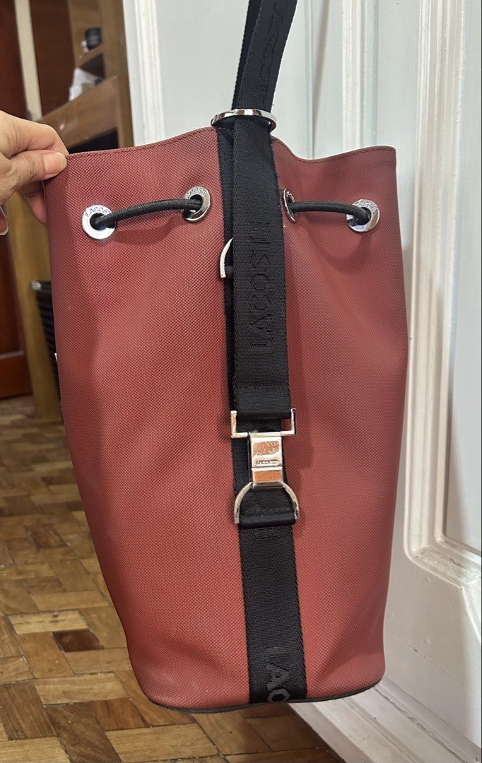 Original Lacoste bucket bag (Category: Cross-body Bags) located in Meycauayan. Submitted by ms.einz (Listing ID 1468340800, Image 3). Description: - Brand: Lacoste Original - Color: Brick red with black branded strap - Closure: Drawstring with metal Lacoste hardware - Interior: Black fabric lining with zip and slip pockets - Condition: Clean and well-maintained #lacoste #lacostebag #lacostebucketbag #lacostedrawstringbag.