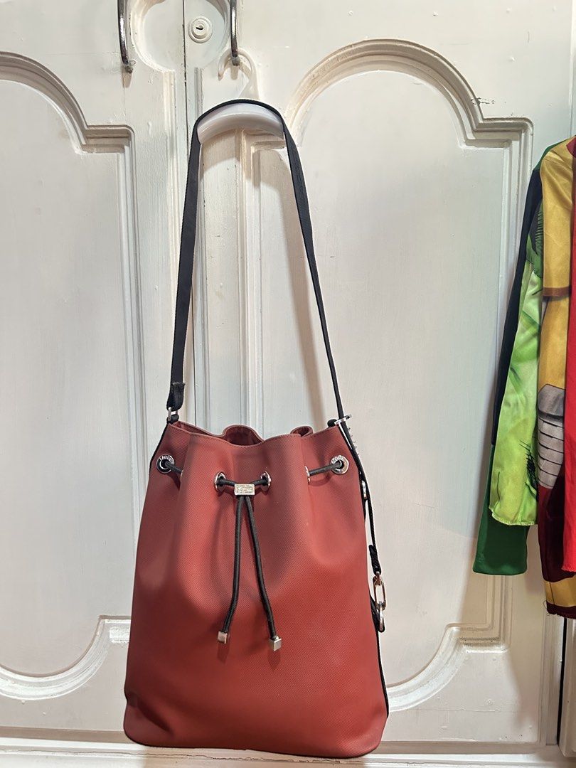 Original Lacoste bucket bag (Category: Cross-body Bags) located in Meycauayan. Submitted by ms.einz (Listing ID 1468340800, Image 1). Description: - Brand: Lacoste Original - Color: Brick red with black branded strap - Closure: Drawstring with metal Lacoste hardware - Interior: Black fabric lining with zip and slip pockets - Condition: Clean and well-maintained #lacoste #lacostebag #lacostebucketbag #lacostedrawstringbag.