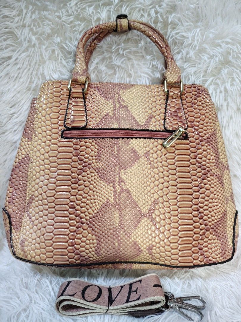 Pink and beige snakeskin pattern handbag with shoulder strap (Category: Cross-body Bags) located in Quezon City. Submitted by zhelcloset01 (Listing ID 1468498399, Image 2). Description: - Trendy pink and beige snakeskin print design - Dual top handles plus a detachable strap with cute 'LOVE' lettering - Elegant gold-tone hardware accents - Spacious dark purple fabric lining with multiple compartments and zippered pockets - Convenient back zipper 
