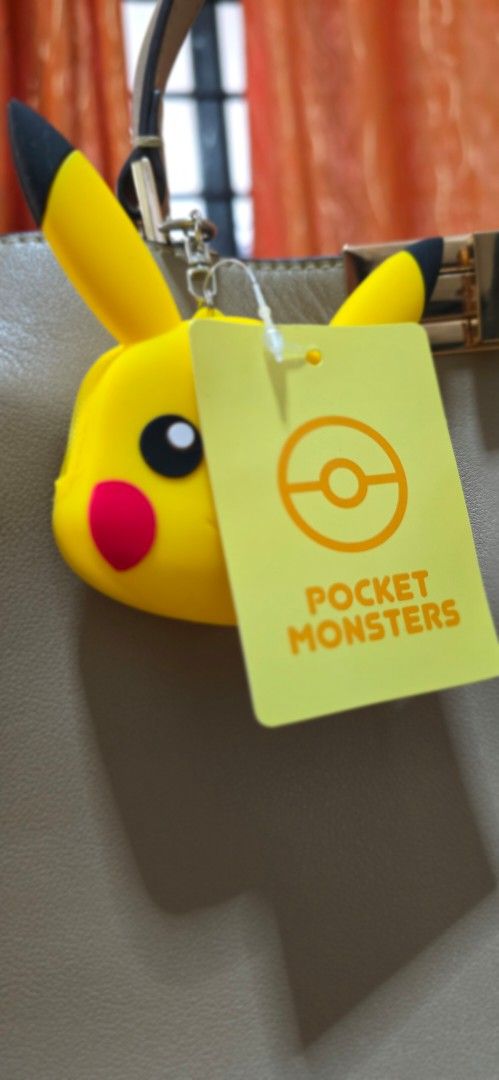Pokémon Pikachu Silicone Mini Pouch Keychain (Category: Character Goods) located in Quezon City. Submitted by curatedbymissgee (Listing ID 1468294912, Image 3). Description: - 100% Authentic Pokémon merchandise with original hang tag attached - Made of soft, durable yellow silicone featuring Pikachu's iconic face and ears - Back includes embossed Pikachu No. 025 text and branding - Equipped with a silver-tone lobster clasp and keyring for easy cl