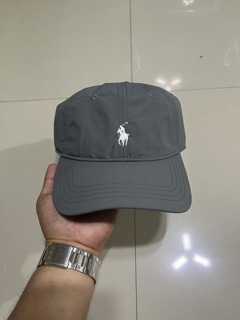 Polo Ralph Lauren Gray Cap (Category: Caps & Hats) located in Quezon City. Submitted by flip_da_cash (Listing ID 1468450513, Image 1). Description: - Brand: Polo Ralph Lauren - Material: Lightweight gray nylon with inner mesh lining - Design: White embroidered pony logo on front, 'POLO' embroidery above back strap - Closure: Adjustable metal buckle stamped with logo - Details: Includes blue brand tag inside - Condition: Excellent, ready to wear -