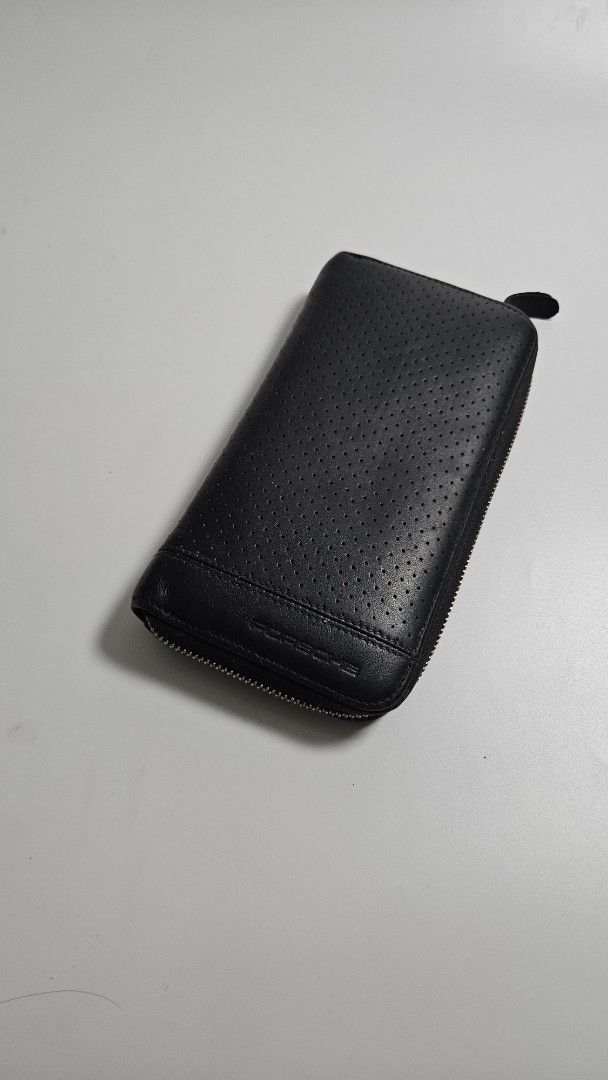 Porsche Design Black Leather Zip Around Wallet (Category: Wallets & Card holders) located in Alfonso. Submitted by jbcamet (Listing ID 1468389333, Image 1). Description: - Brand: Porsche Design - Material: Genuine black leather with stylish perforated pattern - Closure: Secure full zip-around with smooth silver-tone hardware - Interior Features: Multiple card slots, currency compartments, and a zippered coin pocket - Lining: Fabric with subtle Po