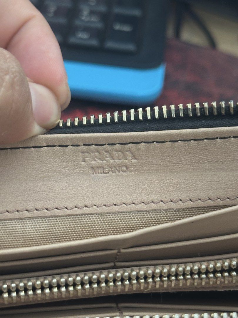 Prada Black Leather Bow Zip Around Wallet (Category: Luxury Bags & Wallets) located in Bustos. Submitted by theprelovedshopbulacan (Listing ID 1468343989, Image 3). Description: - Authentic Prada zip-around long wallet in classic black leather - Elegant gold-tone hardware with cute leather bow and Prada lettering - Contrast nude beige leather lining inside - Multiple card slots, spacious bill compartments, and a zippered coin pocket - Includes in