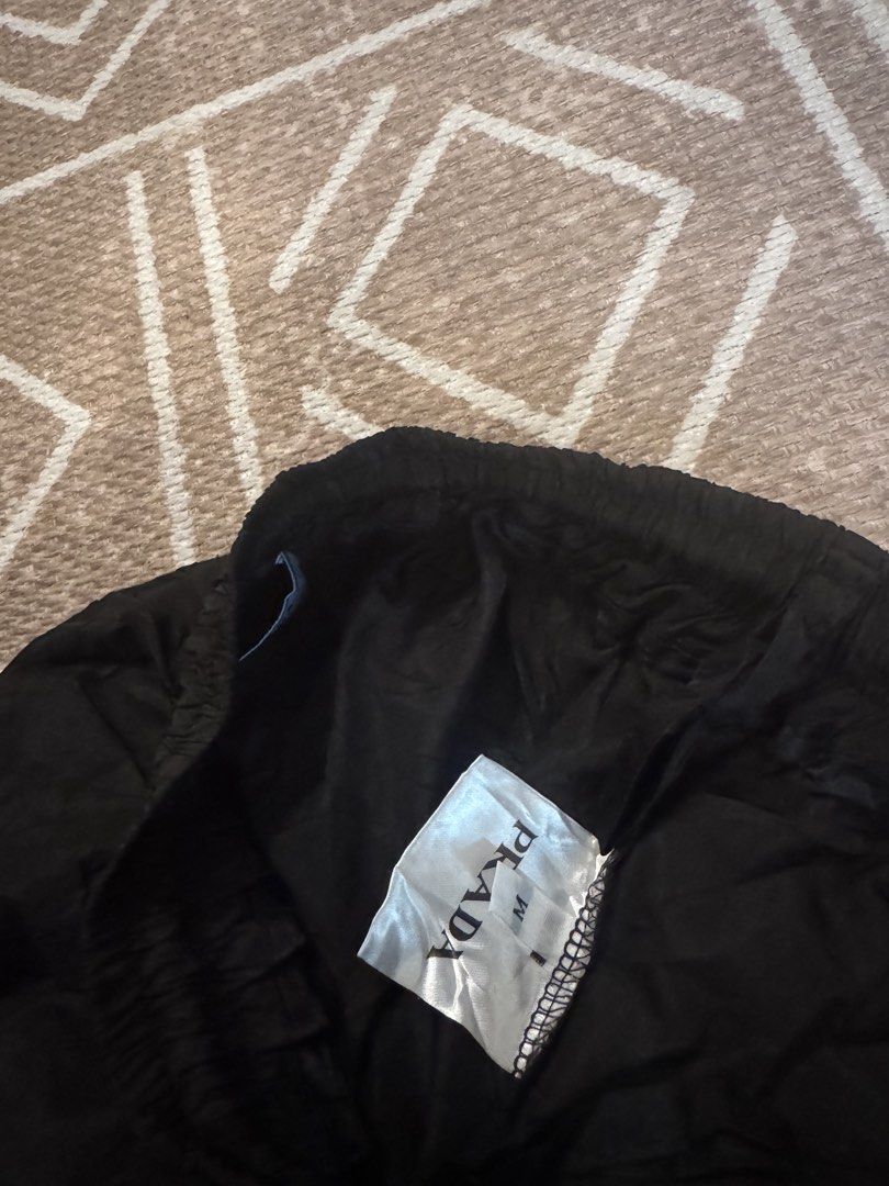 Prada Black Nylon Shorts Size M (Category: Shorts) located in Bulacan. Submitted by zyannechlo86360 (Listing ID 1468343116, Image 3). Description: - Color: Black - Material: Lightweight nylon - Size: Medium (M) - Waistband: Elastic with adjustable drawstring - Branding: Iconic Prada triangular metal logo plaque on left hem - Condition: Brand new with interior brand and care tags attached - Style: Simple slip-on.