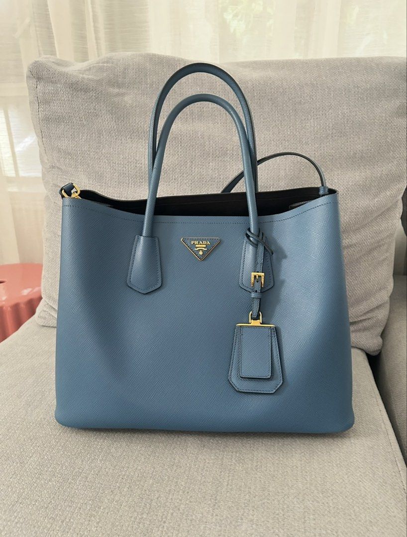 Prada Saffiano Blue Tote Bag (Category: Luxury Bags & Wallets) located in Paranaque City. Submitted by balofies (Listing ID 1468443267, Image 1). Description: - Authentic Prada Saffiano leather tote in a gorgeous blue shade - Elegant gold-tone hardware and signature metal triangle logo plaque - Structured design with clean corners and pristine structure - Double top handles plus an attached long strap for shoulder carry - Open top design with a s