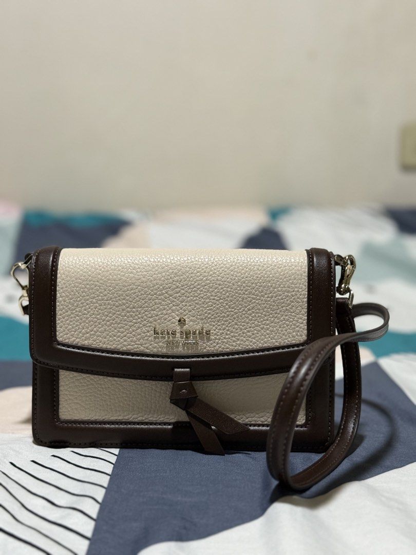 Preloved: Kate Spade Knott Mini Flap Crossbody (Category: Cross-body Bags) located in Makati City. Submitted by rain-san (Listing ID 1468307046, Image 2). Description: - Brand: Kate Spade New York - Style: Two-tone leather crossbody bag - Color: Cream with dark brown trim - Details: Gold foil logo stamping, secure knotted strap detail, and polished gold-tone hardware - Strap: Adjustable dark brown shoulder strap - Size: Compact, perfect for every
