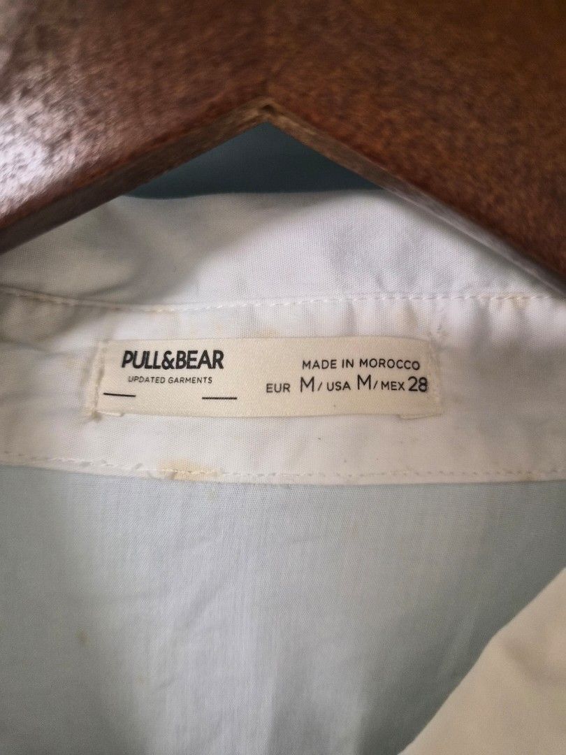 Pull&Bear White Button-Up Shirt Dress Size M (Category: Dresses) located in Manila. Submitted by prelovedbyc.hannah (Listing ID 1468358224, Image 3). Description: - Brand: Pull&Bear - Style: White button-down shirt dress - Size: M (EUR/USA M, MEX 28) - Features: Long sleeves with buttoned cuffs, classic collar, front button closure, and laced side waist details for an adjustable fit - Condition: Noticeable yellowing stains around the inner collar