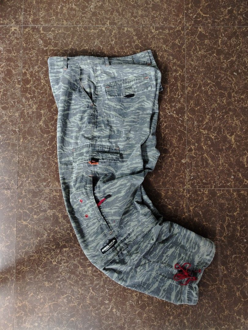 Quiksilver Tiger Camo Zip-off Cargo Pants (Category: Jeans) located in Alegria. Submitted by goofy_ripper (Listing ID 1468374575, Image 3). Description: - Brand: Quiksilver - Style: Grey tiger camouflage cargo pants with versatile zip-off design (converts into shorts) - Features: Multiple functional pockets, stylish red pull cords on zippers and leg cuffs, and signature woven Quiksilver logo patch on the cargo pocket - Closure: Classic button fly